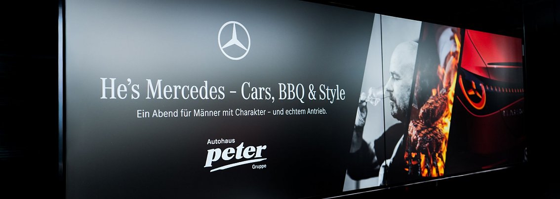 Ein schwarzes Banner mit dem Mercedes-Logo und der Aufschrift He�s Mercedes � Cars, BBQ & Style. Ein Abend f&uuml;r M&auml;nner mit Charakter � und echtem Antrieb. Rechts sind ein Mann mit Weinglas, ein Grillfeuer und der Scheinwerfer eines Mercedes-Autos abgebildet.