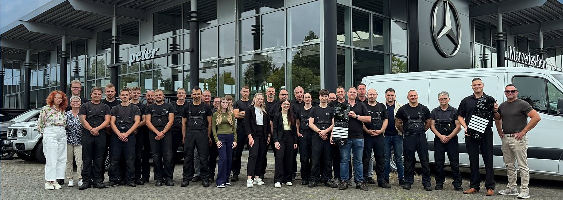 Das Service-Team aus Dessau steht vor dem Mercedes-Benz Center. Zwei Kollegen halten die Auszeichnung in den H&auml;nden. Im Hintergrund sind Autos zu sehen.