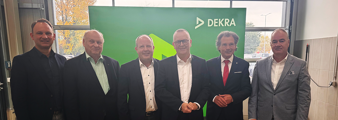 6 Personen im Anzug vor einem gr&uuml;nen Dekra Banner