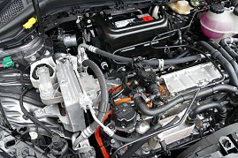 Blick in den Motorraum eines E-Fahrzeuges. Gut zu erkennen sind die Hochvolt-Trennstelle (grün) und die HV-Kabel (orange).