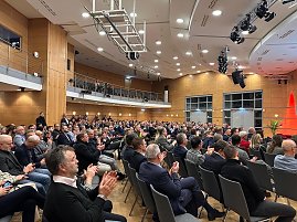 Große Ansicht des Publikums: Zahlreiche Gäste sitzen im Saal und applaudieren während der Eröffnung.