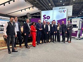 Eine große Gruppe von Männern und einer Frau posiert gemeinsam für ein Foto vor einem Stand der Firma TEAG Mobil auf der Automobilmesse Erfurt 2025. Im Hintergrund sind ein Elektroauto, ein Ladegerät und Werbebanner zu sehen.