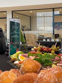 Nahaufnahme eines Buffets mit belegten Br&ouml;tchen, Obst, Gem&uuml;se und K&auml;seplatten. Daneben steht ein Begr&uuml;&szlig;ungsaufsteller zum �koda Unternehmerfr&uuml;hst&uuml;ck.