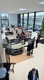 Blick von oben auf den neuen �koda Elroq im Showroom. G&auml;ste stehen um das Fahrzeug, schauen hinein oder diskutieren. Links im Bild ein Pr&auml;sentationsbildschirm.