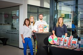 Vier Personen stehen hinter einem Infostand im �koda Autohaus. Auf dem Tisch liegen Brosch&uuml;ren und ein Gl&uuml;cksrad. Die Personen tragen Kleidung mit Logos des Deutschen Roten Kreuzes.