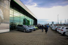 Das �koda Autohaus mit moderner Glasfassade. Vor dem Geb&auml;ude stehen mehrere neue �koda-Fahrzeuge, Besucher gehen zwischen den Autos hindurch.