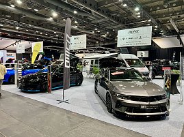 Zwei moderne Opel-Modelle, ein schwarzer und ein grauer Wagen, stehen auf der Ausstellungsfl&auml;che der Autohaus Peter Gruppe. Im Hintergrund Wohnmobile und gro&szlig;e Banner.