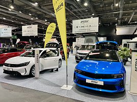 Vorne ein wei&szlig;er Opel Corsa und daneben ein blauer Opel Astra, beide mit ge&ouml;ffneten T&uuml;ren und Kofferr&auml;umen auf der Messe pr&auml;sentiert.