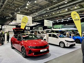Ein roter Opel Astra und ein wei&szlig;er Opel Grandland Hybrid stehen nebeneinander auf der Ausstellungsfl&auml;che, mit Opel-Fahnen und Peter-Bannern im Hintergrund.