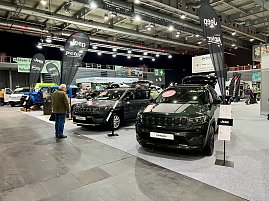 Zwei schwarze Jeep Compass Modelle mit ge&ouml;ffneten Motorhauben und Jeep-Bannern stehen nebeneinander, Besucher betrachten die Fahrzeuge.