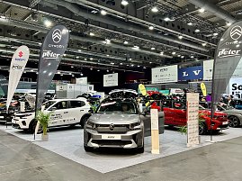 Ein grauer Citro&euml;n SUV und ein wei&szlig;er Citro&euml;n C3 sind ausgestellt, mit Citro&euml;n-Fahnen und weiteren Markenst&auml;nden im Hintergrund.