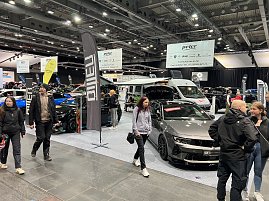 Blick auf mehrere Opel-Fahrzeuge, darunter ein grauer Opel mit offener Motorhaube und ein Wohnmobil. Besucher laufen &uuml;ber die Messefl&auml;che.