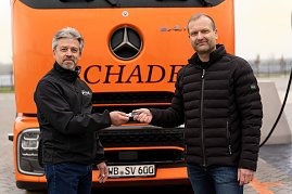 Schl&uuml;ssel&uuml;bergabe: Frank Hentschel, Verkaufsleiter Trucks bei Autohaus Peter GmbH, &uuml;bergibt symbolisch den Fahrzeugschl&uuml;ssel an Bj&ouml;rn Schade, Gesch&auml;ftsf&uuml;hrer Schade Logistics. Beide stehen vor einem orangefarbenen eActros.