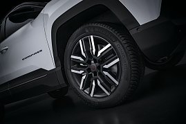 Nahaufnahme des Vorderrads eines wei&szlig;en Jeep Compass mit schwarzer und silberner Leichtmetallfelge, Michelin CrossClimate-Reifen und sichtbarem Compass-Schriftzug an der Seite.