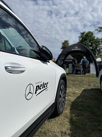 Wei&szlig;er Mercedes-Benz mit Logo: Seitliche Nahaufnahme eines wei&szlig;en Mercedes-Benz mit Autohaus-Peter-Logo, im Hintergrund der Messestand.