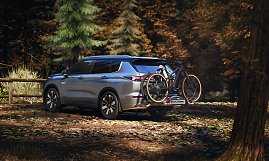 Mit Fahrradträger: Heckansicht des Mitsubishi Outlander mit montiertem Fahrradträger und zwei Fahrrädern, geparkt in einem Waldgebiet.
