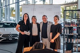 Drei Frauen und ein Mann Personen posieren vor einer Sponsorenwand im Autohaus, darunter Geschäftsführerin Christina Dost und Friseurmeister Oliver Heinicke.