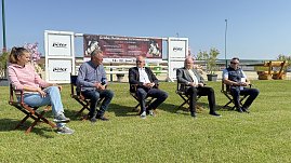 Fünf Personen sitzen auf Stühlen im Freien auf dem Reitplatz in Immenrode während der offiziellen Pressekonferenz zum Reitturnier 2025. Hinter ihnen ist ein großes Banner mit Informationen zum Turnier vom 18. bis 22. Juni zu sehen. Sonniges Wetter und grüne Rasenfläche prägen die Szene.