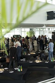 Blick in den Ausstellungsraum des Autohauses Peter beim s&uuml;dafrikanischen Abend in Heiligenstadt. Zahlreiche G&auml;ste stehen in Gruppen zusammen, unterhalten sich und genie&szlig;en die entspannte Atmosph&auml;re zwischen dekorierten Stehtischen und Fahrzeugen.