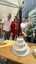 Helmut und Andreas Peter, der kostümierte Roland und eine Mitarbeiterin der Bäckerei stehen hinter der Jubiläumstorte