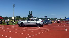 Einfahrt der Sportstars beim Leichtathletik-Meeting Anhalt 2025: Ein silberner Mercedes-Benz SUV des Autohauses Peter fährt über die rote Laufbahn, ein Sportler winkt aus dem geöffneten Schiebedach. Dahinter stehen weitere Fahrzeuge und Eventfahnen.