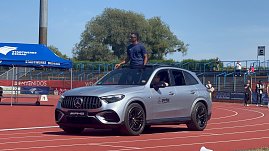 Ein silberner Mercedes-Benz SUV des Autohauses Peter fährt auf der roten Laufbahn beim Leichtathletik-Meeting Anhalt 2025. Ein Sportler steht aus dem geöffneten Schiebedach, im Hintergrund sind Zuschauertribünen und ein blaues Stadtwerke-Dessau-Zelt zu sehen.
