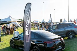 Besucher schlendern &uuml;ber die Wiese des Reitturniers in Immenrode mit wei&szlig;en Pagodenzelten und Getr&auml;nkest&auml;nden. Im Vordergrund stehen zwei Mercedes-Benz Fahrzeuge neben Fahnen des Autohauses Peter.