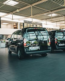 Ein schwarzer Opel-Transporter steht in einem hellen Autohaus mit großen Glasfenstern.