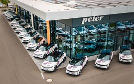 Mehrere weiße Opel Grandland mit schwarzen Dächern stehen in aufgereiht vor dem Autohaus Peter in Erfurt mit großer Glasfassade. Auf den Fahrzeugen sind auffällige Werbeaufkleber mit den Logos THC und Peter und weiteren Sponsoren zu sehen.