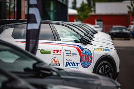 Nahaufnahme einer Reihe weißer Opel-SUVs mit schwarzem Dach, die nebeneinander auf einem Parkplatz stehen. Auf der Fahrertür des vordersten Fahrzeugs sind zahlreiche Logos zu sehen, darunter THC Thüringer Handball Club, Autohaus Peter, TMP Fenster + Türen, Joma, Universal Bau und weitere.