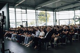 Reihe neuer Auszubildender der Autohaus-Peter-Gruppe sitzt in der Firmenzentrale in Nordhausen. Alle tragen schwarze T-Shirts mit Firmenlogo und h&ouml;ren der Auftaktveranstaltung aufmerksam zu.