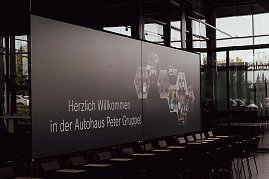Leinwand mit der Begr&uuml;&szlig;ung �Herzlich willkommen in der Autohaus Peter Gruppe!� in der Firmenzentrale in Nordhausen. Auf der Leinwand sind auch Fotos von Mitarbeitern und Azubis zu sehen.