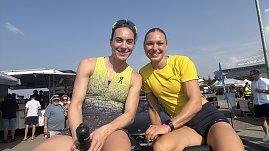 Zwei Sportlerinnen sitzen auf der Rückbank eines Mercedes-Cabrios und lächeln in die Kamera. Beide tragen Sportkleidung, die linke ein gelb-graues Top, die rechte ein gelbes Shirt. Im Hintergrund Zuschauer und Zelte beim Leichtathletikmeeting in Sondershausen.