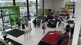 „Blick von oben in den Ausstellungsraum des Autohauses Autowelt Peter während der Jubiläumsfeier zu 130 Jahren koda. Besucherinnen und Besucher schauen sich verschiedene Fahrzeuge an, Mitarbeitende in grünen Shirts beraten. Im Hintergrund steht eine bunte Hüpfburg für Kinder.