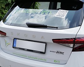 Das Heck eines weißen koda-Fahrzeugs mit der Aufschrift „Wir stellen ein.“ und einem QR-Code auf der Heckscheibe. Darunter ist das Logo der Klinik zu sehen.