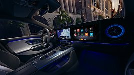 Das Bild zeigt einen weißen Mercedes-Benz CLA Shooting Brake, der auf einer breiten, nahezu leeren Stadtstraße fährt. Moderne Gebäude umgeben die Szene, das Licht wirkt weich und frühmorgendlich. Der Wagen ist seitlich zu sehen und vermittelt Dynamik sowie Eleganz.