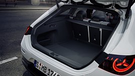 Das Bild zeigt einen weißen Mercedes-Benz CLA Shooting Brake, der auf einer breiten, nahezu leeren Stadtstraße fährt. Moderne Gebäude umgeben die Szene, das Licht wirkt weich und frühmorgendlich. Der Wagen ist seitlich zu sehen und vermittelt Dynamik sowie Eleganz.