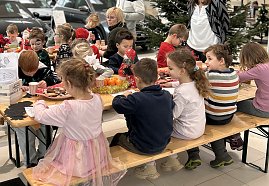 Kita-Kinder sitzen an Biertischgarnituren und basteln Baumschmuck