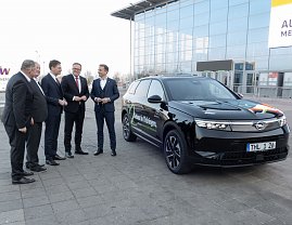 Fünf Männer im Anzug stehen vor der Messehalle neben einem schwarzen Opel-SUV mit der Aufschrift Gebaut in Thüringen.