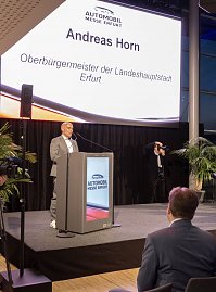 Mann am Rednerpult auf der Bühne der Automobil Messe Erfurt, Leinwand zeigt Andreas Horn, Oberbürgermeister Erfurt.