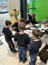 Drei Jungen stehen an einem Infotisch der Polizei, zwei Polizistinnen geben Materialien und Buttons aus.