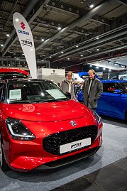 Roter Suzuki auf der Automesse, zwei Besucher begutachten das Fahrzeug.