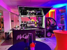 cCaf&eacute;-Kaffeebar im Eventbereich mit buntem Licht und Stehtischen.