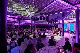 Gala-Event mit B&uuml;hne, Rednern und Publikum an gedeckten Tischen.