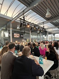 Die Gäste schauen sich an Hochtischen einen Film an, der auf einer Leinwand abgespielt wird.