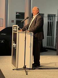 Helmut Peter begrüßt die Gäste auf der Bühne am Rednerpult.