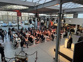 Der Blick von der Galerie auf die Veranstaltung: Helmut Peter am Rednerpult, viele Gäste hören ihm zu.