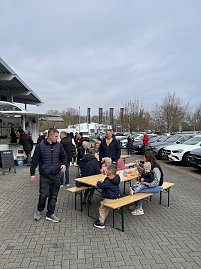 Besucher des Ostermarktes lassen es sich drau&szlig;en auf Bierzeltgarnituren schmecken.