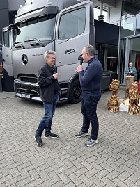 Frank Hentschel und Ren&eacute; Pfeuffer stehen vor dem Actros, beide am Mikrofon und erkl&auml;ren technische Details der Sattelzugmaschine.