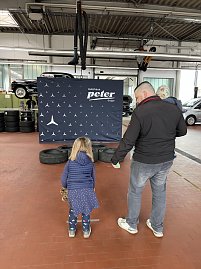 Ein M&auml;dchen wirft in einer Werkstatt Sands&auml;ckchen in Autoreifen.